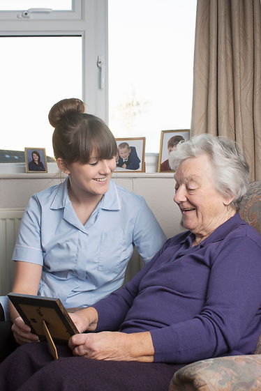 Personal care assistant looking at photograph with senior woman