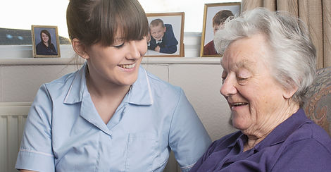 Personal care assistant looking at photograph with senior woman