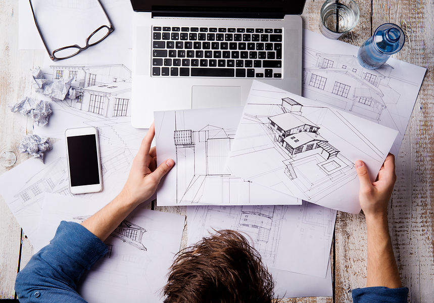 Overhead view of a person examining architectural sketches at a desk
