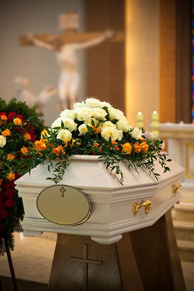 White coffin decorated with white flowers inside a chapel