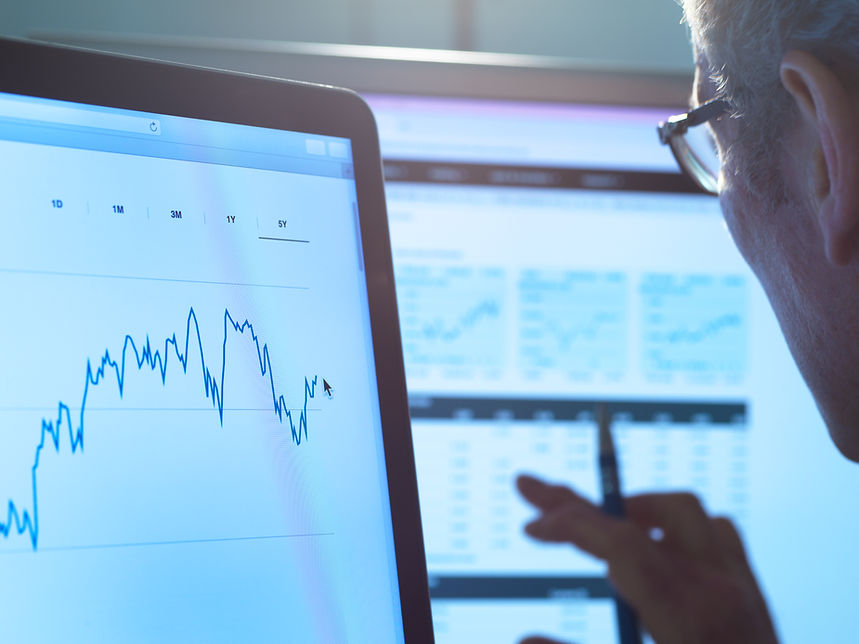 A person analyses financial data on computer monitors