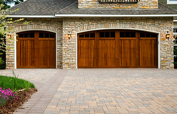 Pavers, wood custom garage doors, landscaping and beautiful stone exterior walls on a cust