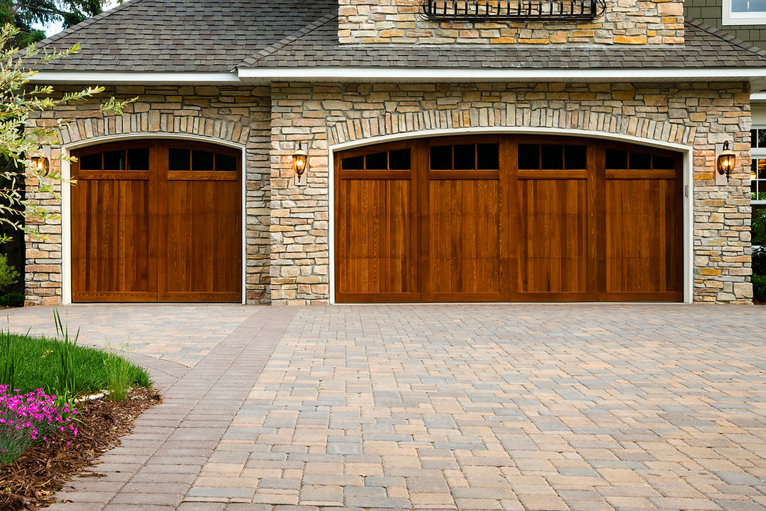 Pavers, wood custom garage doors, landscaping and beautiful stone exterior walls on a cust