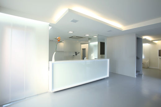Sleek minimalist reception area featuring an illuminated white desk with recessed overhead lighting