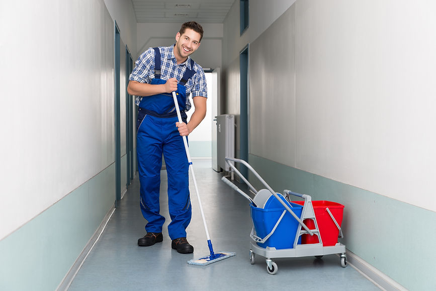 A person with a mop cleaning a corridor