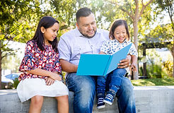adult male reading to two children