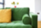 Close-up of a green sofa with a cushion in a room