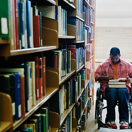 Young black male using wheelchair Reading Books in Library