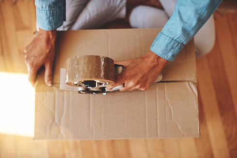 Cropped shot of a woman sealing a box with adhesive tape at home