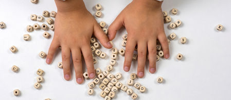 Mains d'enfant posées sur des lettres de l'alphabet dispersées