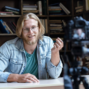 Smiling man recording video in library