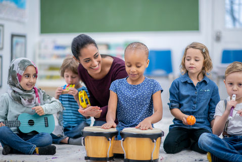 Teacher and diverse children playing musical instruments.