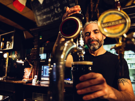 Traditional bartender serving beer from tap