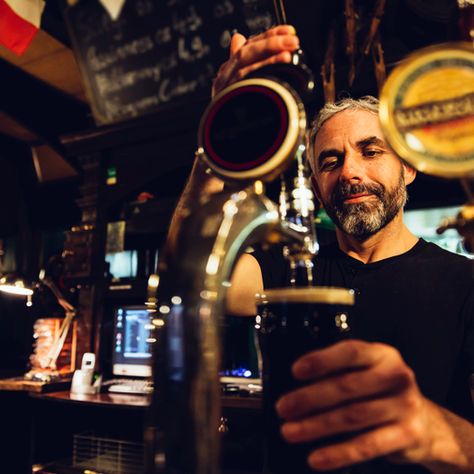 Traditional bartender serving beer from tap