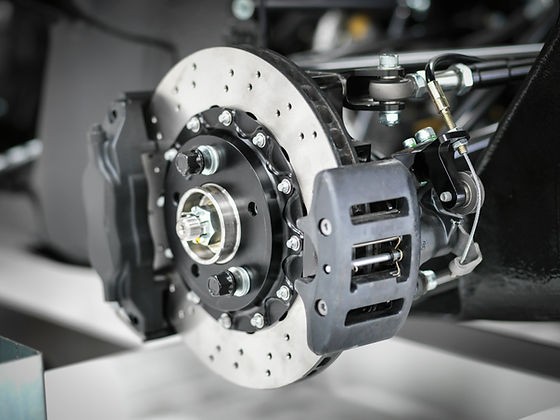 Close up view of a high performance ventilated car brake disc rotor fitted with a black caliper
