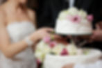 A bride and a groom is cutting their wedding cake