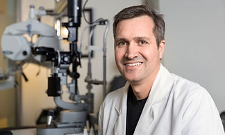 Portrait of happy male optometrist sitting in clinic