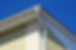 Close-up of a building's corner featuring white eaves and gutters 