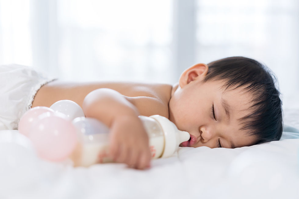 A baby boy sleeping beside a milk bottle