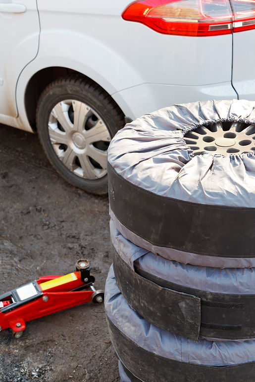 seasonal replacement of car tyres with jack outdoors - set of summer tyres