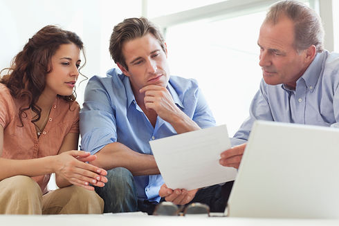 Three people sit at a table in discussion, focused on a document