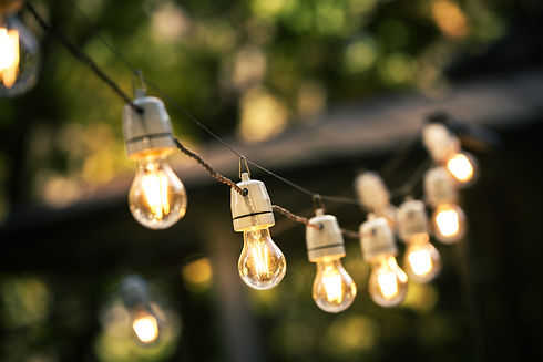 Decorative outdoor festoon string lights glowing brightly in a garden during twilight hours