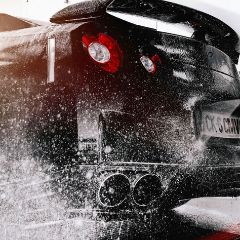 a black car going through a car wash and getting hosed down