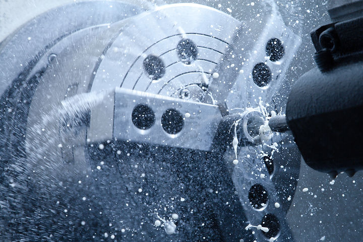 A CNC machine processes metal, spraying coolant fluid