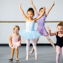 Children in a dance class smiling, jumping, and having fun.
