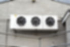 Commercial HVAC unit with three cooling fans mounted on a wall