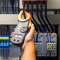Electrician measuring voltage or current by voltmeter in control panel