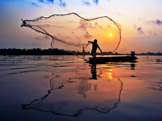 fisherman at sunset with large net