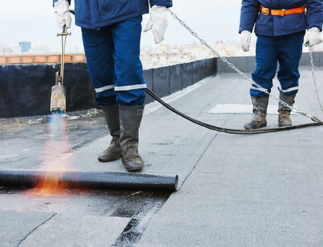 Two professionals installing a flat roof on a building