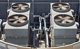 Rooftop cooling units feature four large ventilation fans and interconnected grey pipes