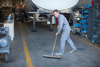 An industrial worker sweeping the floor