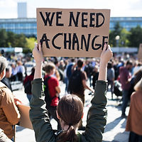 A woman holding up a sign that reads "We Need a Change"