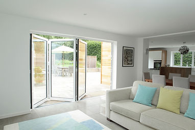 A white living room with bi-fold doors opening to a garden.
