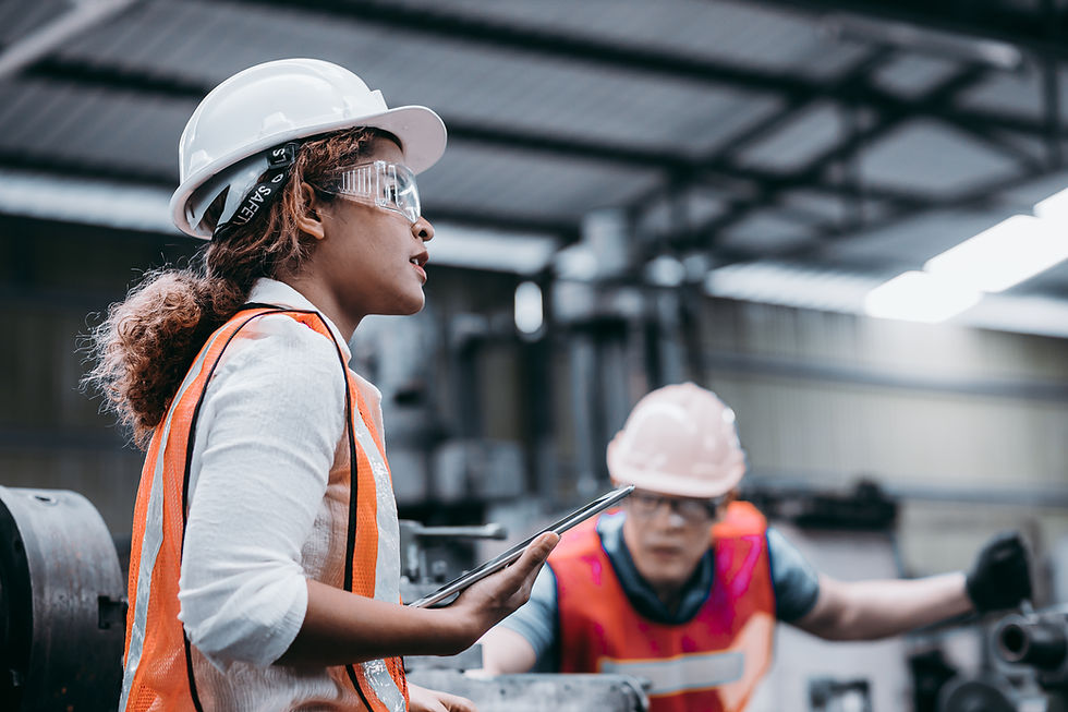 Femme en casque de sécurité instruisant un collègue dans une usine.
