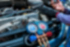 Mechanic using a manifold gauge set on a car engine