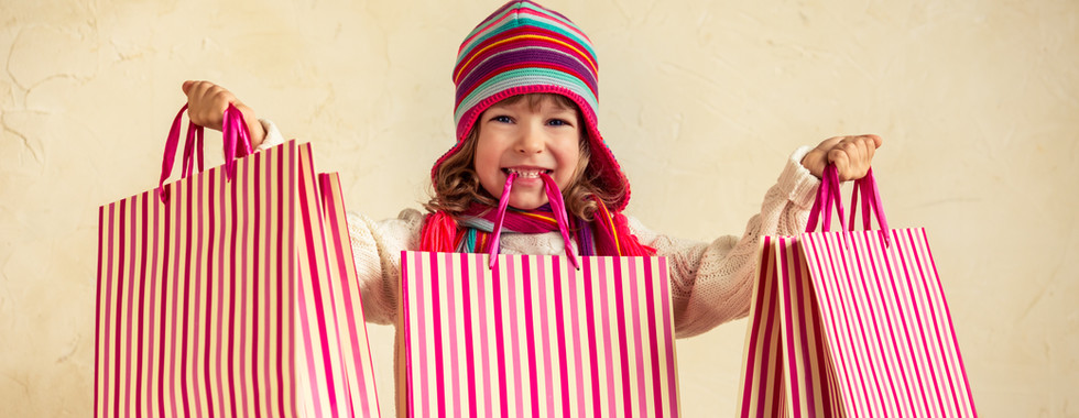 LITTLE GIRL HOLDING RED AND WHITE STRIPED SHOPPING BAGS