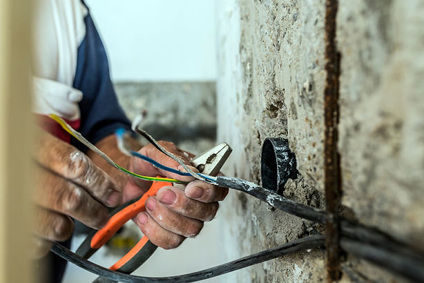 Photo of Electrician peeling off insulation from wires - closeup on hands and pliers. elec