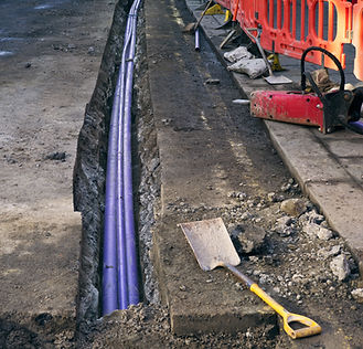 A construction site with three purple electrical cables laid in a trench