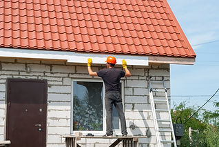 A man is diligently working on the roof of a house.
