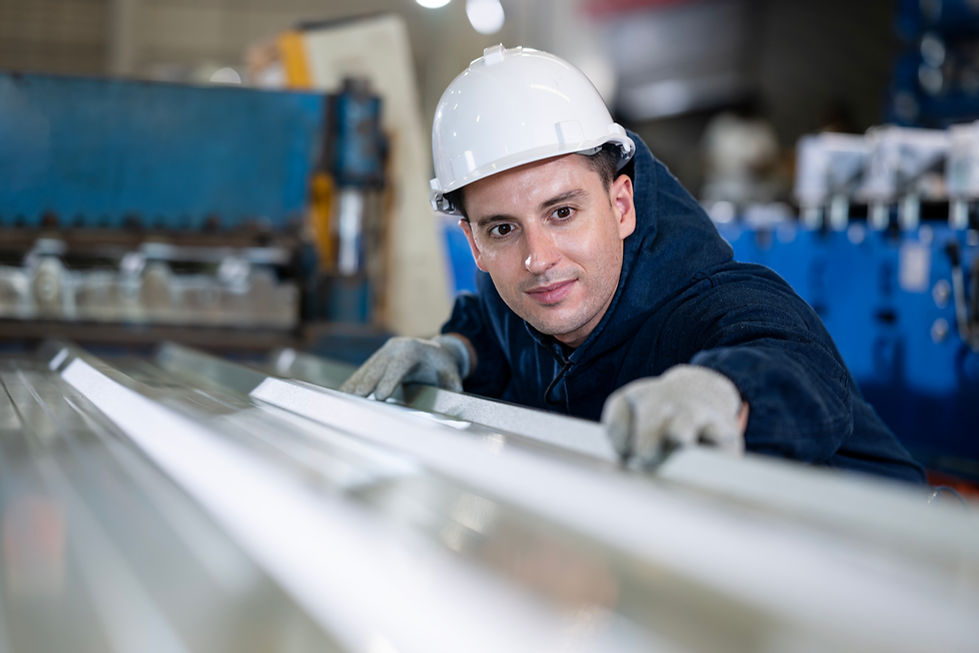 A man  inspects metal sheets in a workshop