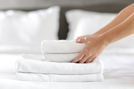 Professionelle Reinigungskraft bezieht ein Bett mit makellos sauberer Wäsche in einer Ferienunterkunft.