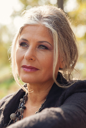 Middle aged white woman with silver blonde hair looking in the distance supporting early breast cancer detection..