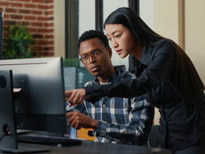 Two professionals using a computer to research South African labour law cases, representing the ALLU 2026 BotBuddy AI tool for finding court judgments, understanding employment law and applying legal precedents in workplace decisions.