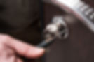 Close up of locksmith using screwdriver to install cylinder lock on wooden door