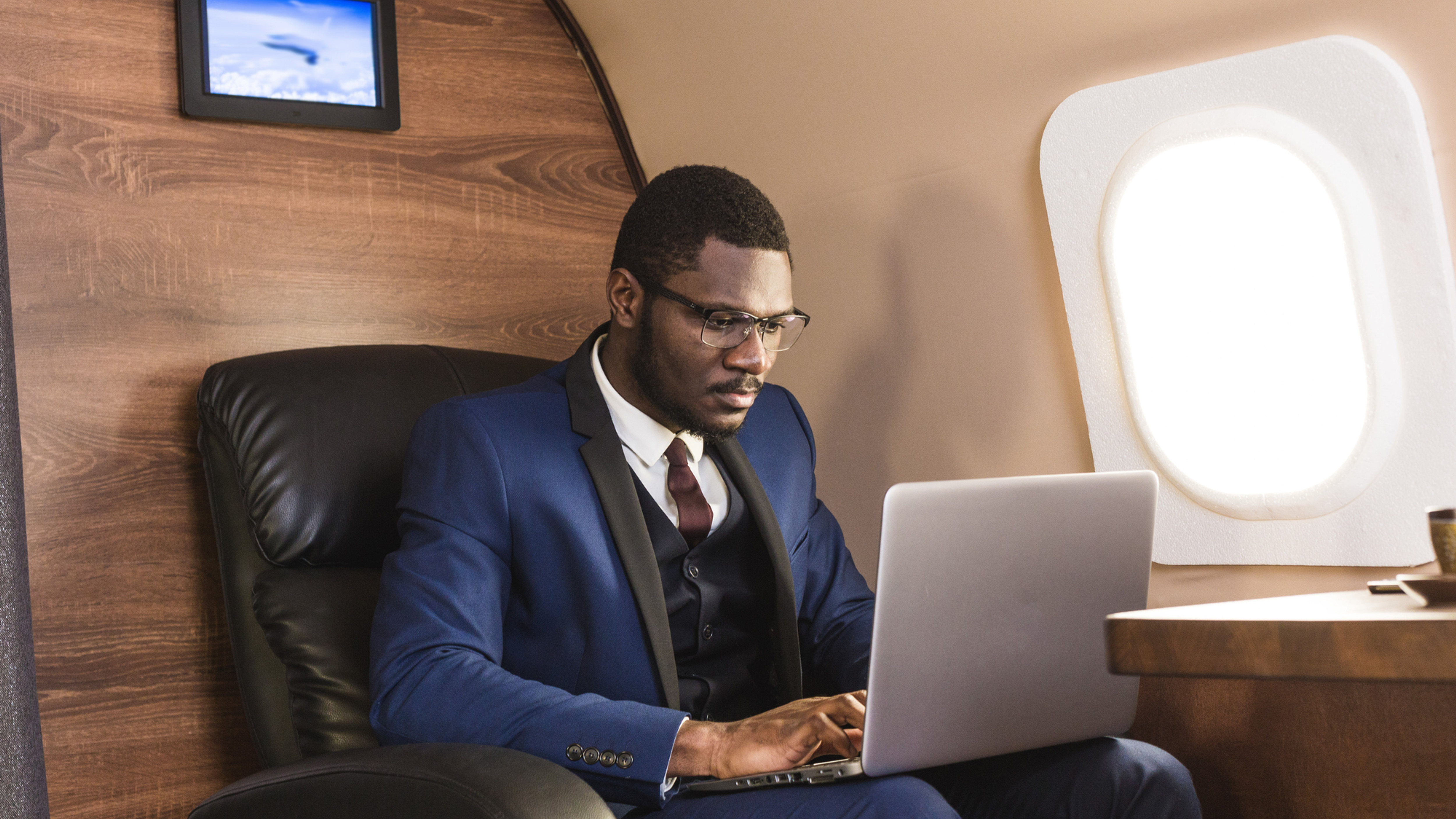 Businessperson reviewing a laptop while seated in an aircraft cabin