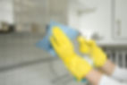 Close-up of a person's hands in rubber protective yellow gloves cleaning the kitchen
